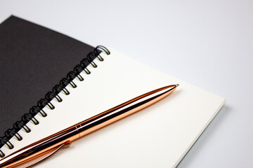 Elegant luxury golden color metal pen on notepad.Black notepad with empty sheet and gold pen.Stationery concept.