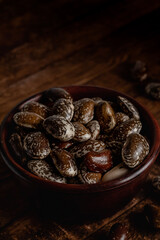 Dark bowl with dry brown scarlet runner beans on a wooden background. Close up.