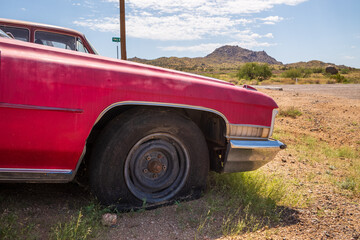 rusting old caldillac with a broken wheel