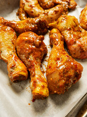 Close up shot of Asian style marinated chicken wings and drumstick ready to be cooked on a white cooking paper and metal tray. Chicken meat poultry product.