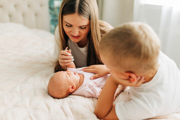 Lifestyle family portrait of parents with newborn baby child and older son. Happiness and love at home indoors