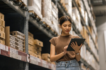 Young female manager worker checklist manage parcel box product in warehouse. Asian woman supervisor using tablet working at store industry. Logistic import export concept. - obrazy, fototapety, plakaty