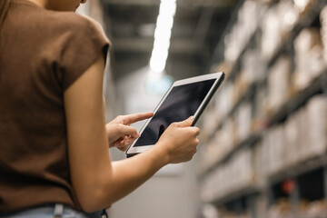 Young female manager worker checklist manage parcel box product in warehouse. Asian woman supervisor using tablet working at store industry. Logistic import export concept.