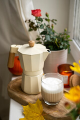 Moka pot and a glass of coffee on the windowsill. Autumn mood