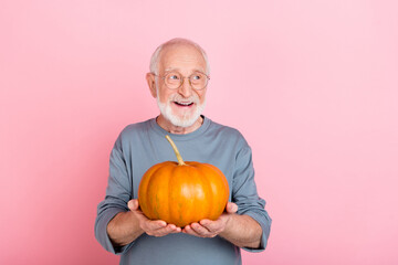 Photo of cool aged white hairdo man hold pumpkin look ad wear eyewear blue pullover isolated on...