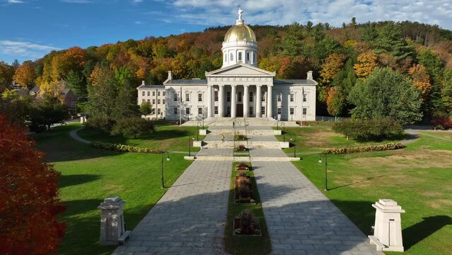 Vermont State House surrounded by fall trees. Aerial dolly forward tilt up towards capitol building.