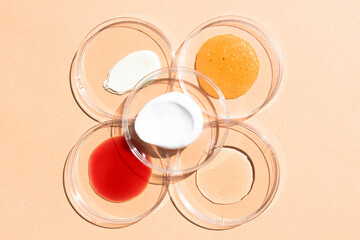 Cosmetic samples of body cream, hyaluronic acid, peptide, scrub on a beige background top view.