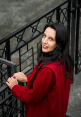 brunette woman in red coat with red lips walking in autumn Kyiv city