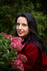 Naklejka premium portrait of a brunette woman with red lips with rosw flowers
