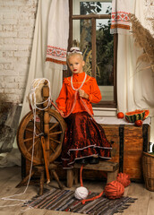 girl in a Cossack costume stand in a hut near the window
