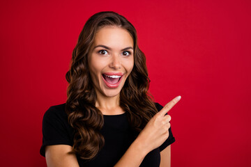 Obraz premium Photo of shiny impressed young lady dressed black t-shirt smiling pointing finger empty space isolated red color background