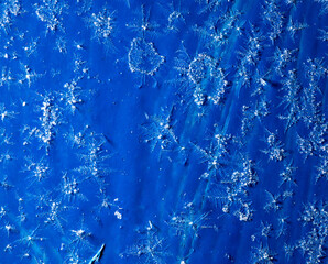 White snowflakes on a blue metal sheet.