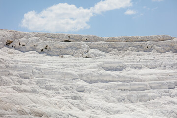 A mountain of white volcanic limestone rock against a blue sky.