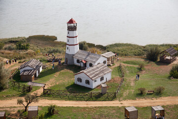 Merzhanovo, Russia: beautiful old lighthouse and wooden buildings on the sandy seashore of the Taganrog Bay, autumn, 2022. Set for the film "The Lighthouse Keeper".
