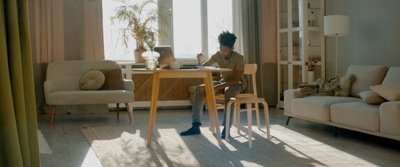 WIDE HANDHELD African American Black kid boy doing his homework or having a video call with class and teacher. Distance learning from home during isolation. Shot with 2x anamorphic lens