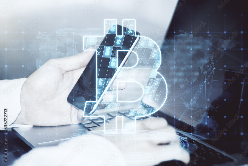 Poster close up of businessman hands holding cellphone and using laptop with creative glowing bitcoin holog