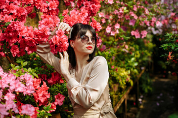 A bright girl in glasses and a short dress among blooming azaleas
