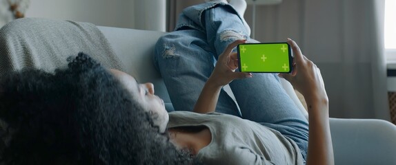 GREEN SCREEN CHROMA KEY DOLLY IN Black African American female lying on sofa, holding phone in...