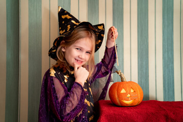 a little girl in a masquerade witch costume with a pumpkin lantern for Halloween