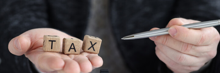 Inscription tax on cubes and businessman holds pen