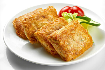 Crepes with stuffing and salad in a white plate. Close-up, selective focus. White background