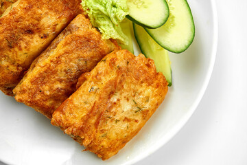 Crepes with stuffing and salad in a white plate. Close-up, selective focus. White background