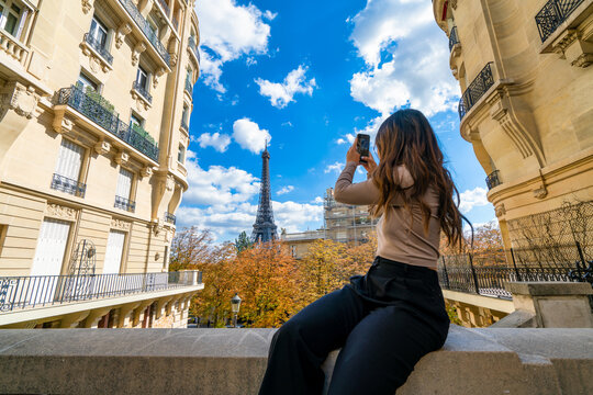 Holidays in Paris. Eiffel Tower in autumn season seen by female tourist taking picture - focus on the tower 