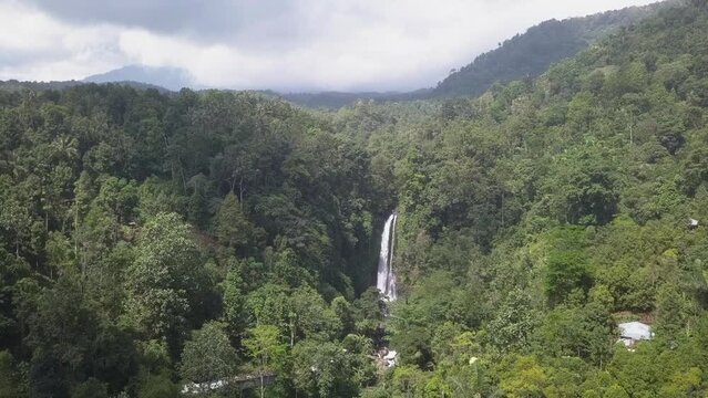 North Bali dense jungle valley flight toward dramatic tall waterfall