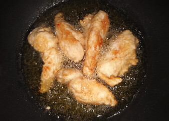 Fried chicken in hot oil. Top view of food in pan. Home cooking.