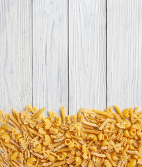 Different types and shapes of Italian pasta on white wooden background