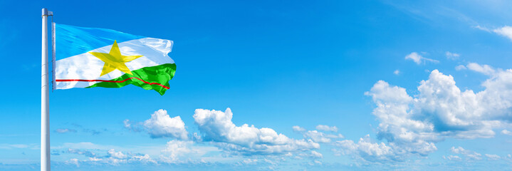 Roraima - state of Brazil, flag waving on a blue sky in beautiful clouds - Horizontal banner