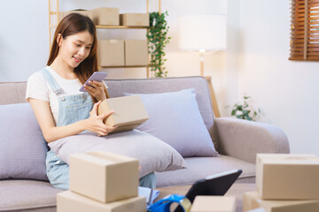 Obraz na płótnie Canvas Online shopping concept, Female entrepreneur use smartphone to take picture parcel boxes to client