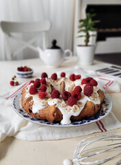 Round cake made of rice flour and cottage cheese, decorated with white icing, walnut crumbs and fresh raspberries. Homemade cakes are served with tea or coffee.