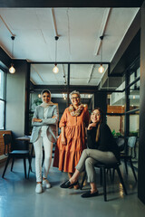 Three diverse businesswomen smiling at the camera in an office