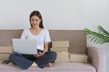 Online selling concept, Asian business woman checking online orders on laptop to prepare delivery