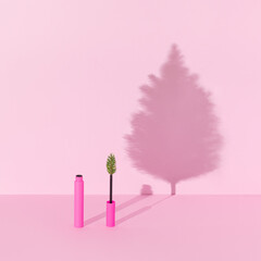 Creative winter makeup composition made with pink mascara with Christmas three branch and Christmas tree shadow against bright pink background. Minimal New Year fashion beauty party concept.