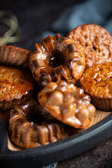 Homemade delicious chocolate mini cakes on the wooden plate on the table with coffee and christmas decoration. Close up