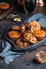 Homemade delicious chocolate mini cakes on the wooden plate on the table with coffee and christmas decoration. Dark and moody