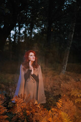 Fototapeta na wymiar Red-haired woman in beige coat in autumn forest