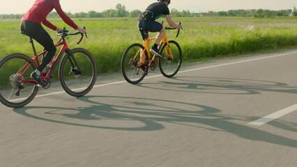 Back view of cyclists pedaling racing bicycles outdoors during sunset. Men in track suits and bicycle helmets enjoying favorite hobby on fresh air.