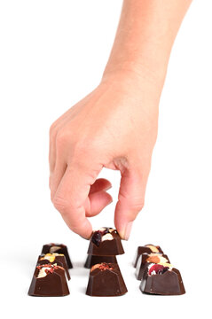 Yummy chocolate candies in the female hand on white background. Different delicious chocolate candies close up