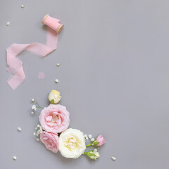 Pink and cream roses and silk ribbons on grey top view, Romantic wedding background