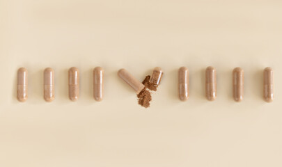 Dietary capsules in a line with one on light beige top view, hard shadows. Dietary supplements