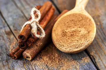 Top view of cinnamon sticks with twine bow and wooden spoon on old table