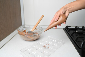 Pastry chef tempering hot chocolate to chocolate molds. Cooking desserts.