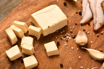 still life of food in a rural style on a dark wood background, sliced cheese and bacon, garlic, salt and pepper, concept of healthy food