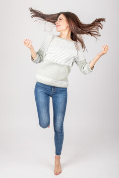 Fashion and lifestyle concept. Studio portrait of beautiful and sexy brunette woman with beautiful body shape wearing bright sweater with short sleeves and blue jeans. Image contain motion blur