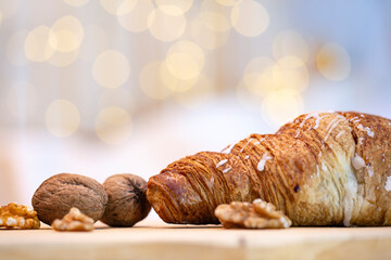 Fresh baked chocolate croissant with walnuts on the table in winter time