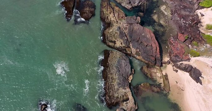A columnar basaltic or rock formation with breaking waves on beach