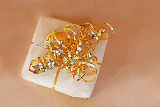 gift wrapped in craft paper with a gold ribbon on a craft background, congratulations.